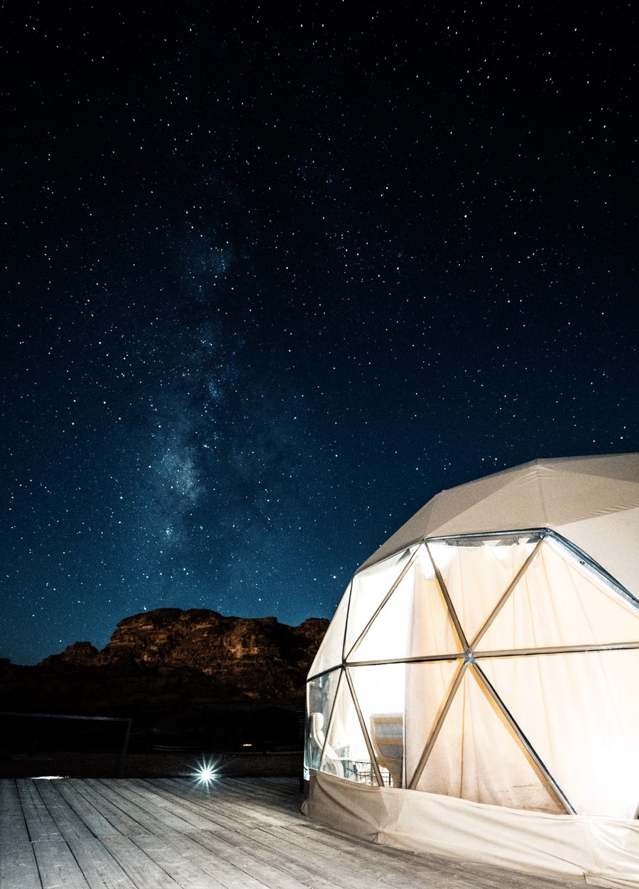 Domo geodésico iluminado bajo un cielo estrellado
